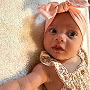 Brooklyn is registered to the contest to win money with this photo: baby, infant, headband, pink_bow, floral_outfit, blanket, soft_texture, curious_expression, wide_eyes, reaching_arm, portrait, close_up, child, cute, indoors, light_shadow, skin, face, person, newborn