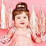 baby, child, infant, portrait, smiling, happy, pink, dress, bow, hair, hands, frosting, cake_smash, birthday, party, backdrop, tassels, indoor, sitting, closeup