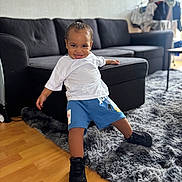 Kessim participe au concours pour gagner de l'argent avec cette photo : black_sneakers, blue_shorts, casual_clothing, child, couch, cozy, floor, furniture, happy, home, indoor, living_room, person, playful, rug, smiling, toddler, white_tshirt, wooden_floor, young_child