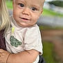 arm, baby, blurred_background, child, closeup, clothing, cute, dinosaur_patch, face, hand, happy, holding, human, infant, nature, outdoor, person, portrait, shirt, smile