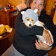 Mia Joanne Smith joined the competition — help win amazing prizes! woman, dog, hat, indoors, clothing, hand, nails, furniture, table, bottle, container, sitting, pet, knit_hat, smiling, tattoo, cozy, casual, person, carpet