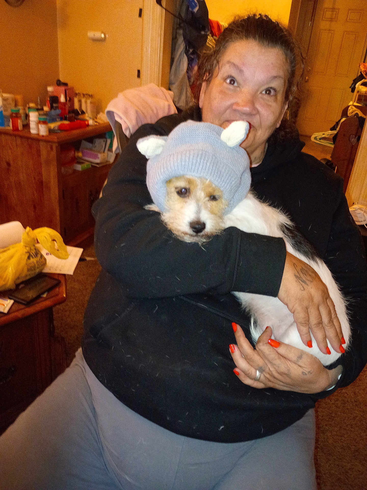 Mia Joanne Smith joined the competition — help win amazing prizes! woman, dog, hat, indoors, clothing, hand, nails, furniture, table, bottle, container, sitting, pet, knit_hat, smiling, tattoo, cozy, casual, person, carpet