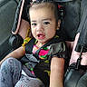 child, toddler, baby, car_seat, car, vehicle, portrait, face, eyes, open_mouth, hair_clips, necklace, harness, seatbelt, colorful_clothing, sitting, indoors, travel, candid,  안전