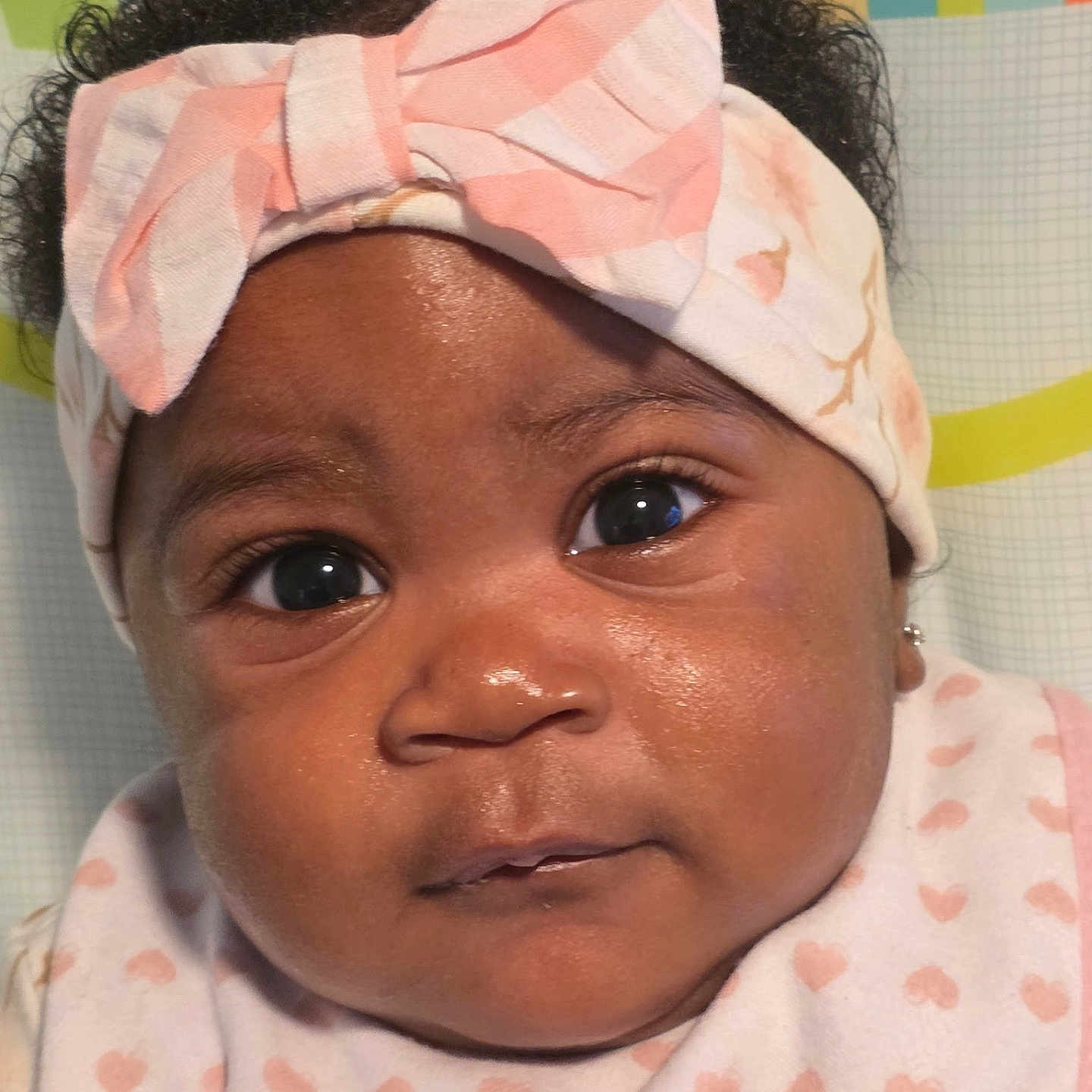 Chioma joined the competition — help win amazing prizes! baby, infant, face, headband, bow, clothing, pink, white, heart_pattern, portrait, closeup, cute, child, person, skin, eyes, expression, indoor, colorful_background, adorable