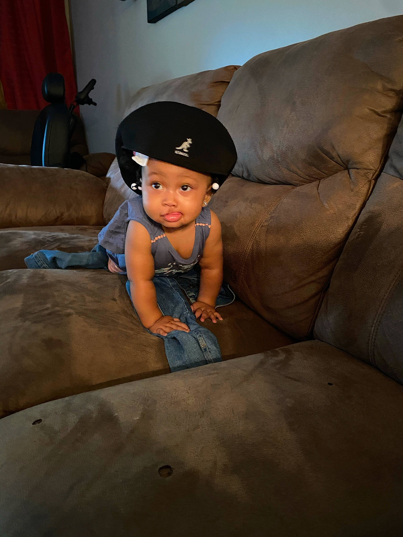 Kori is registered to the contest to win money with this photo: baseball_cap, cap, child, comfort, concrete, couch, eye, fashion_accessory, flash_photography, floor, flooring, fun, hardwood, headwear, leisure, living_room, person, room, sitting, t_shirt