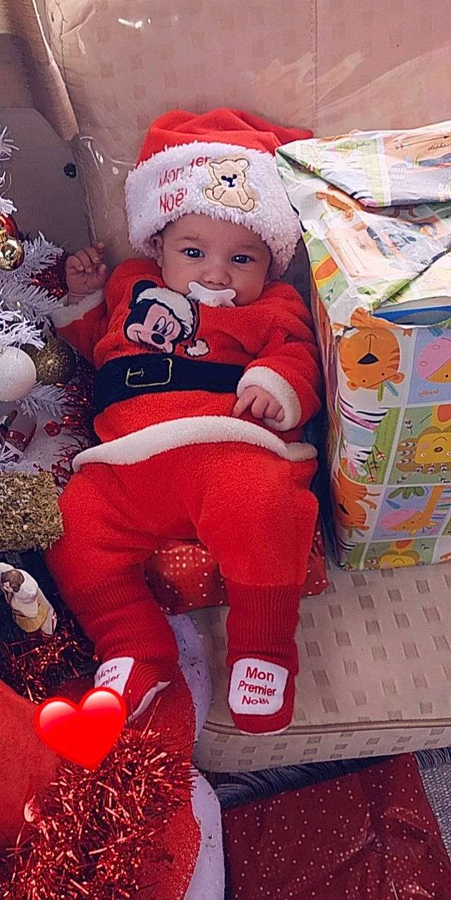 Djelson a rejoint le concours — aidez-le/la à gagner de superbes lots ! baby, baby_products, baby_toddler_clothing, carmine, child, christmas, christmas_eve, christmas_ornament, event, fictional_character, fun, happy, headwear, holiday, lap, person, pink, red, santa_claus, smile