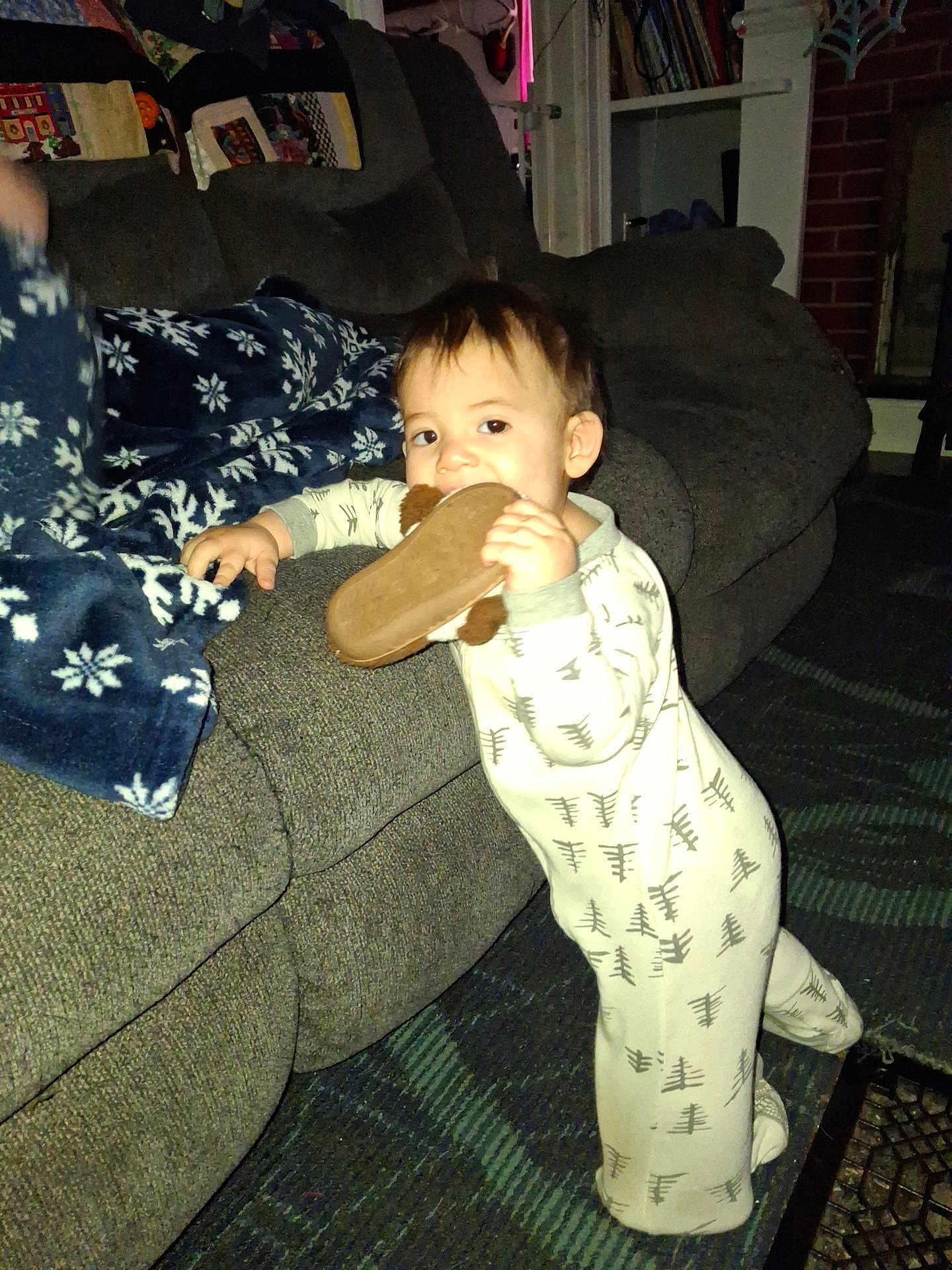 John joined the competition — help win amazing prizes! toddler, child, pajamas, slipper, couch, blanket, living_room, carpet, indoor, furniture, person, face, hand, footwear, home, cozy, smiling, standing, baby, curious