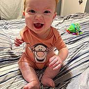 Onyx joined the competition — help win amazing prizes! baby, red_hair, smiling, onesie, cartoon_print, bed, striped_bedspread, toy, indoor, child, happy, sitting, person, infant, cute, barefoot, cheerful, skin, hand, face