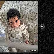 Kimaya is registered to the contest to win money with this photo: baby, infant, face, eyes, hair, pajamas, blanket, pattern, soft, cozy, indoor, portrait, child, cute, looking_up, small_hand, newborn, sleepwear, resting, closeup