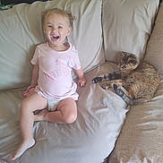 Payge Bertrand a rejoint le concours — aidez-le/la à gagner de superbes lots ! animal, casual, cat, child, clothing, couch, cute, diaper, floor, furniture, happy, home, indoor, light_skin, pet, relaxing, short_hair, sitting, smiling, toddler