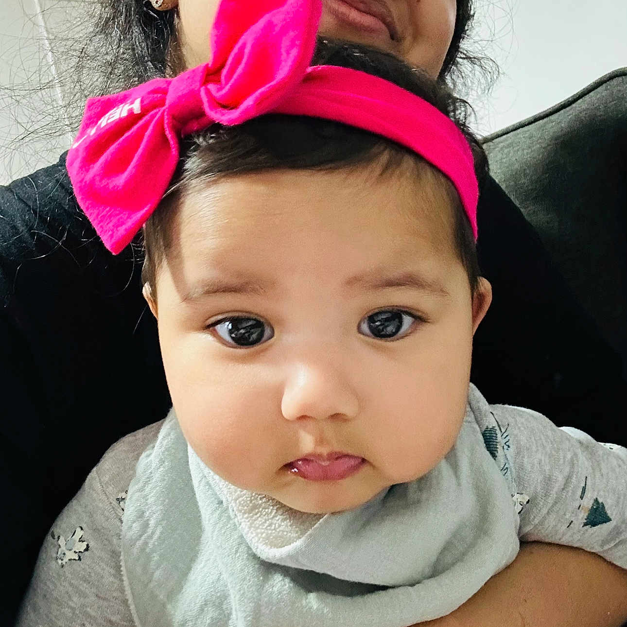 Mehwish is registered to the contest to win money with this photo: adult, baby, bib, child, closeup, clothing, cute, expression, face, family, headband, holding, indoor, love, person, pink_bow, portrait, skin, smile, young