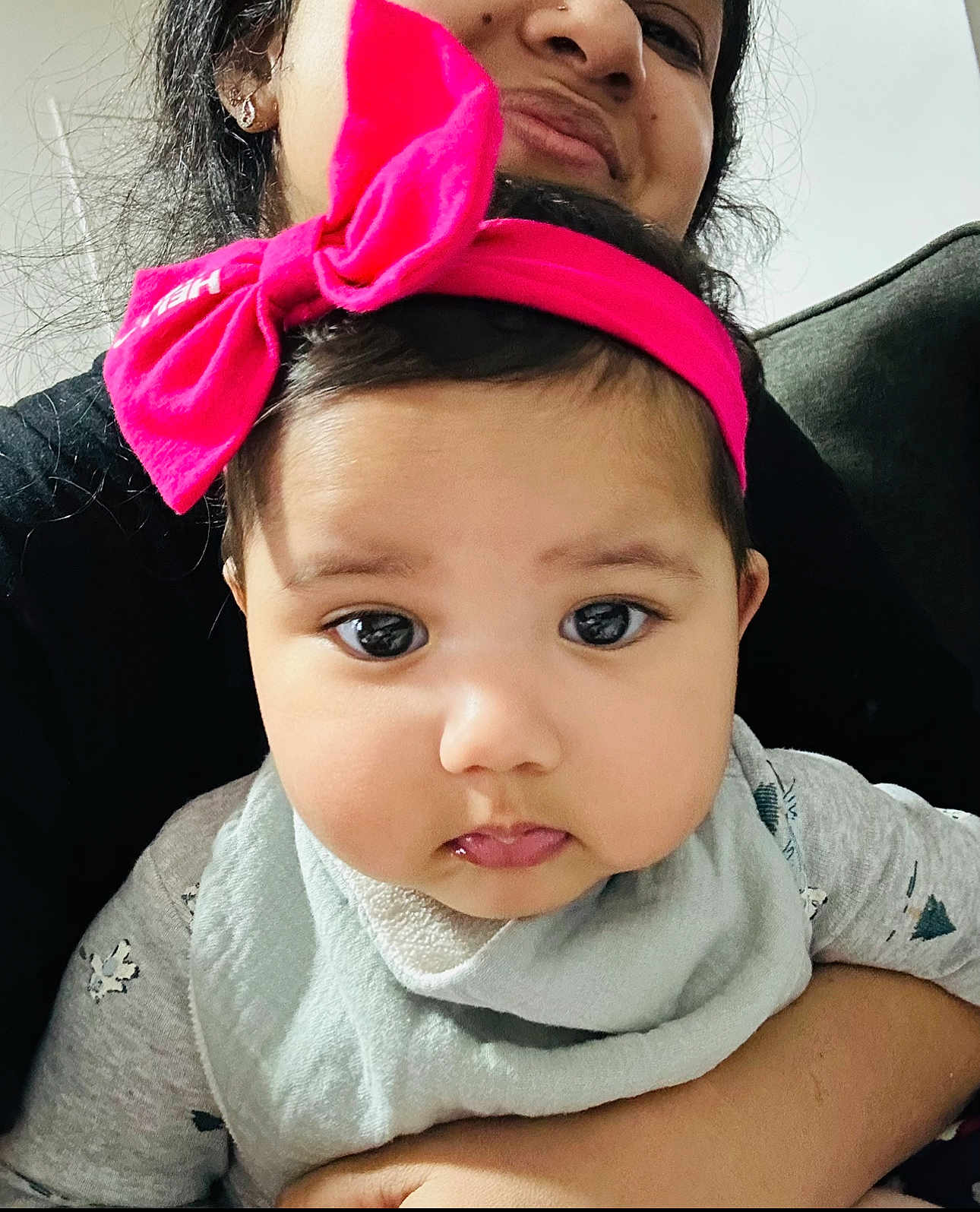Mehwish is registered to the contest to win money with this photo: baby, child, person, face, headband, pink_bow, bib, clothing, adult, holding, smile, portrait, indoor, cute, closeup, skin, expression, young, love, family