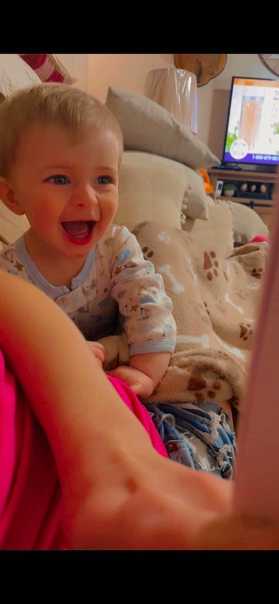 Miles is registered to the contest to win money with this photo: arm, baby_toddler_clothing, cheek, comfort, facial_expression, finger, hairstyle, happy, head, human_body, leg, mouth, neck, nose, person, skin, smile, television, thigh, thumb