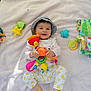 Jaya a rejoint le concours — aidez-le/la à gagner de superbes lots ! baby, child, outdoor, blanket, toy, hat, smile, happy, grass, play, infant, colorful, clothing, person, cute, sunlight, leisure, lying_down, fun, nature