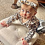 baby, infant, child, crawling, leopard_print, headband, pajamas, cushion, carpet, wooden_furniture, indoor, curious, wide_eyes, cute, person, portrait, hands, face, expression, soft_lighting