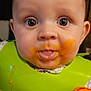 baby, face, food_stain, bib, high_chair, orange, messy, close_up, curious, child, infant, mouth, tongue, eyes, clothing, indoor, person, cute, feeding, expression