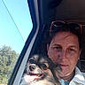 blue_sky, casual_clothing, companion, daytime, dog, face, happy, nature, outdoor, pet, seatbelt, selfie, smiling_dog, sunglasses, sunlight, tongue_out, trees, vehicle, window, woman