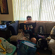 Alyrique joined the competition — help win amazing prizes! child, boy, couch, pillow, living_room, window, blinds, indoors, sitting, portrait, gift_bag, present, fish_tank, aquarium, stuffed_toy, blanket, clutter, furniture, casual, home