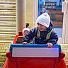 Cruz joined the competition — help win amazing prizes! beanie, child, coat, coin_op_ride, evening, hands, hat, jacket, kid, kiddie_ride, open_daily, outdoor, pavement, play, sign, smile, storefront, stuffed_pig, toddler, toy