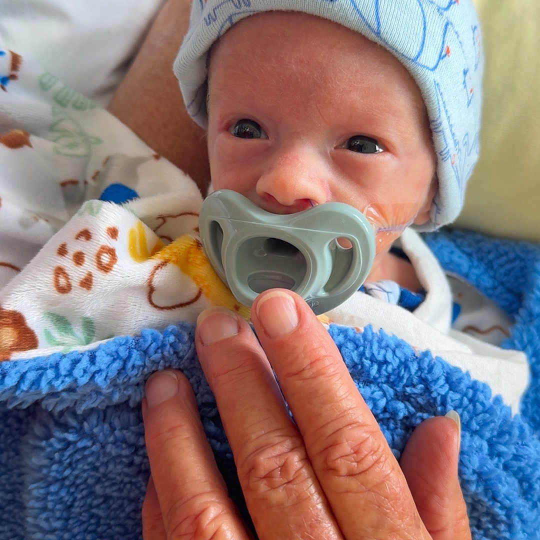 Ruby is registered to the contest to win money with this photo: newborn, baby, pacifier, hand, blanket, hat, hospital, infant, cute, cozy, wrapped, bed, skin, person, resting, closeup, comfort, tiny, care, warm