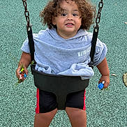 Alex joined the competition — help win amazing prizes! child, toddler, swing, playground, curly_hair, hoodie, shorts, toys, grass, outdoor, play, fun, smiling, person, recreation, seat, chains, ground, casual_clothing, happy