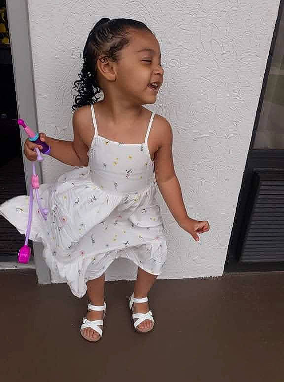 Gabby is registered to the contest to win money with this photo: arm, baby_toddler_clothing, child, day_dress, elbow, fashion_design, finger, foot, fun, gesture, hand, happy, human_leg, pattern, person, room, shoulder, sleeve, smile, toddler