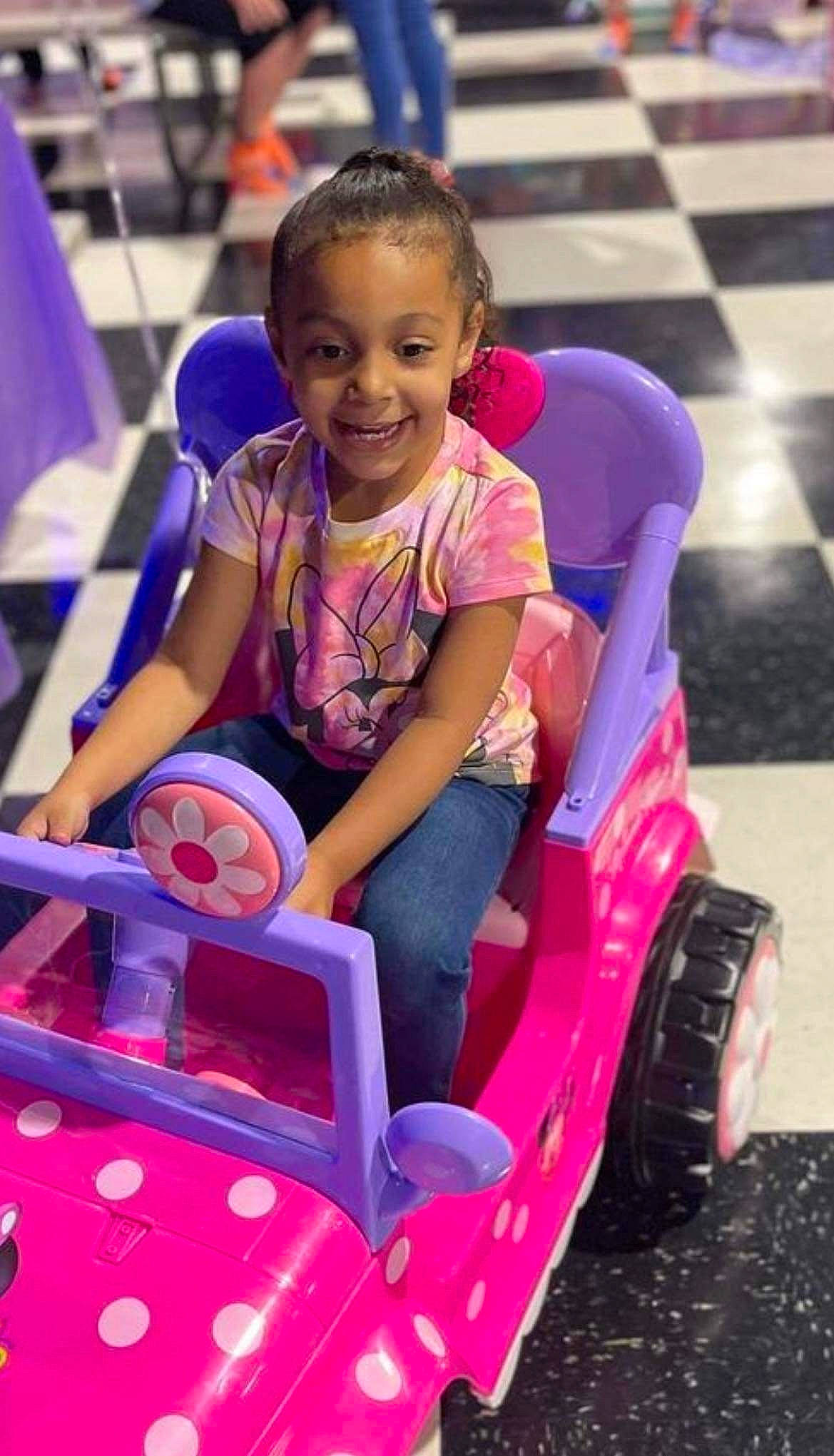 Gabby is registered to the contest to win money with this photo: automotive_tire, beauty, bumper, child, fun, happy, joy, leisure, magenta, motor_vehicle, person, pink, purple, recreation, riding_toy, shorts, smile, snapshot, tire, toddler