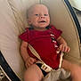baby, infant, smiling, red_shirt, baby_chair, seatbelt, indoors, happy, child, face, skin, human, person, cute, young, one_person, clothing, sitting, baby_boy, expression