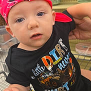 Archer is registered to the contest to win money with this photo: baby, child, bandana, shirt, construction_vehicle, shopping_cart, person, indoor, face, hand, adult_arm, bag, vape, menthol, clothing, looking_at_camera, sitting, retail, shelf, plate
