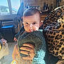 adult_hand, baby, blanket, child, cute, flower_dress, holding, indoor, infant, kitchen, knitted_sweater, leopard_print, person, portrait, rings, seat, smiling, sunlight, tongue_out, window