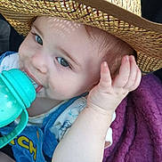 Cayden is registered to the contest to win money with this photo: baby, child, hat, straw_hat, bottle, drink, purple_blanket, blue_clothing, cute, face, hand, infant, sitting, portrait, indoors, closeup, expression, young, person, baby_bottle