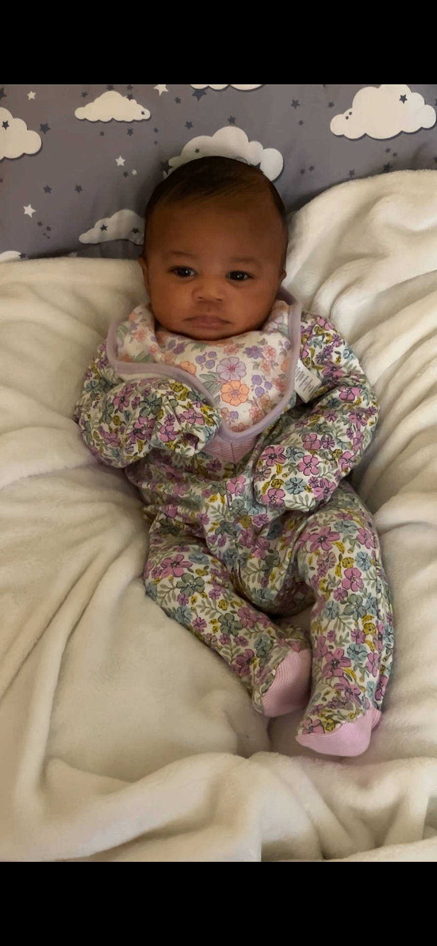 Izhara joined the competition — help win amazing prizes! baby, bib, blanket, child, cloud_pattern, comfort, cute, expression, face, floral_clothing, indoor, infant, lying_down, onesie, plush, portrait, resting, soft_texture, star_pattern, young