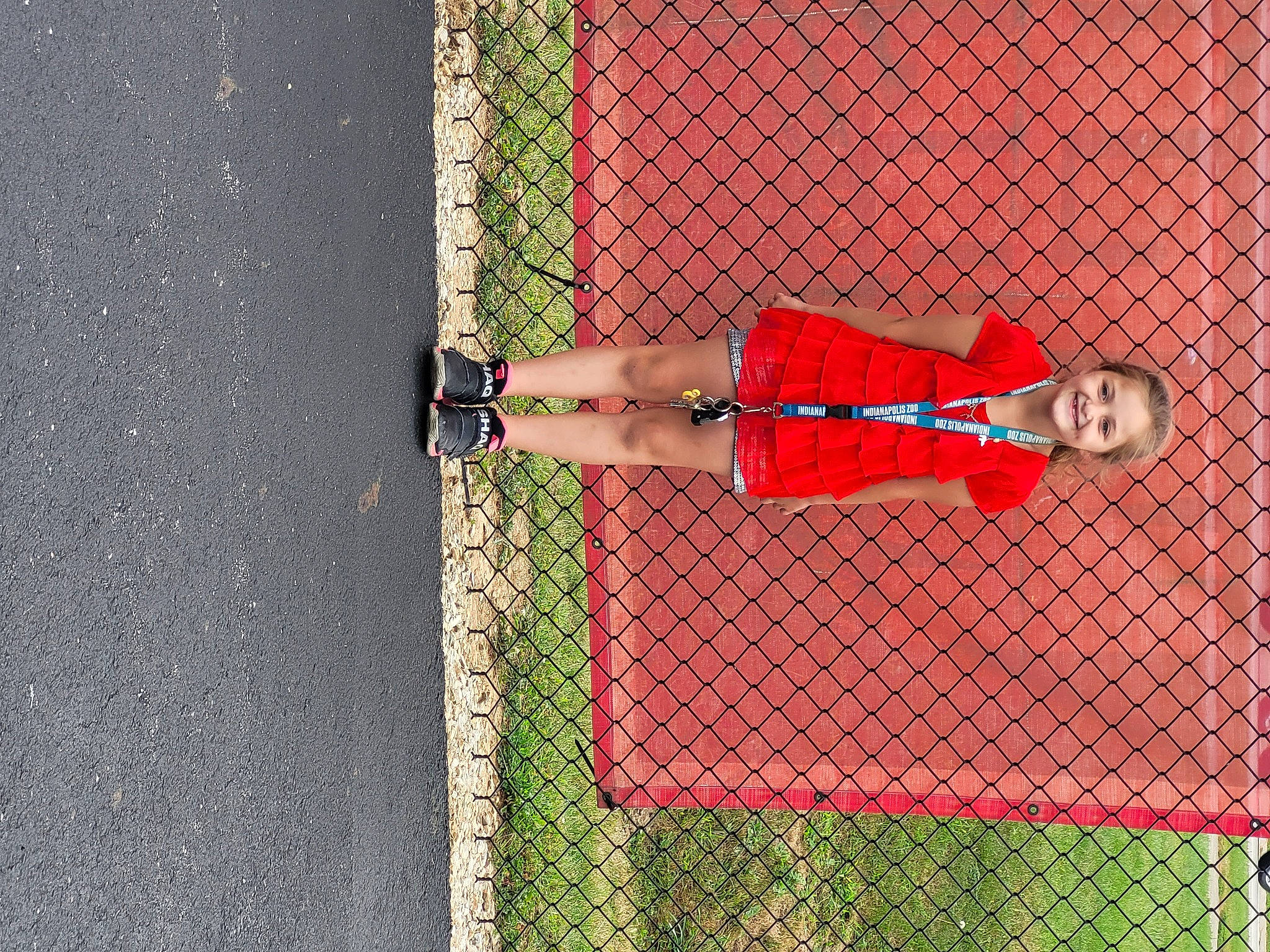 Lexi is registered to the contest to win money with this photo: chain_link_fencing, fence, grass, human_leg, joy, knee, leg, line, mesh, pattern, person, plant, player, red, sneakers, sports, sports_equipment, thigh, tire, tree