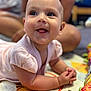 baby, child, infant, smiling, playmat, colorful, face, hands, tongue, clothing, person, background, blurred, happy, cute, indoors, skin, eyes, young, pale_pink