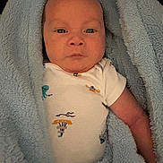 Elijah is registered to the contest to win money with this photo: baby, infant, blanket, blue_blanket, onesie, clothing, face, portrait, child, newborn, wrapped, cute, skin, expression, lying_down, soft_texture, indoor, young_child, head, eyes