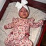 baby, infant, child, onesie, headband, bow, crib, changing_table, blanket, heart_pattern, pink_clothing, ribbon, buttons, awake, eyes_open, portrait, closeup, wood_frame, mattress, indoor_flash