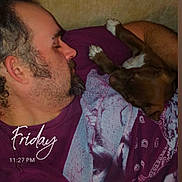 Gemini Wheeler is registered to the contest to win money with this photo: man, dog, sleeping, couch, purple_shirt, beard, piercing, snuggling, indoors, relaxing, pet, cozy, resting, casual, human, animal, comfort, face, arm, text_overlay