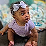 baby, child, infant, bow, headband, purple_onesie, sitting, curious, wide_eyes, indoors, blurred_background, soft_lighting, portrait, cute, small_feet, hands, textured_surface, cozy, warm, adorable