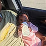 baby, bottle, milk, infant, pink_onesie, curly_hair, car_interior, adult, green_shirt, sunlight, window, seat, person, child, feeding, hand, relaxing, casual, portrait, closeup