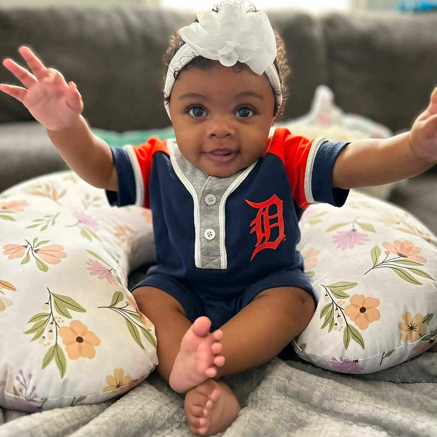 Ryan joined the competition — help win amazing prizes! arms_outstretched, baby, blanket, blue_outfit, child, couch, cute, eyes, feet, floral_pattern, happy, headband, indoors, infant, living_room, orange_detail, pillow, portrait, sitting, smiling