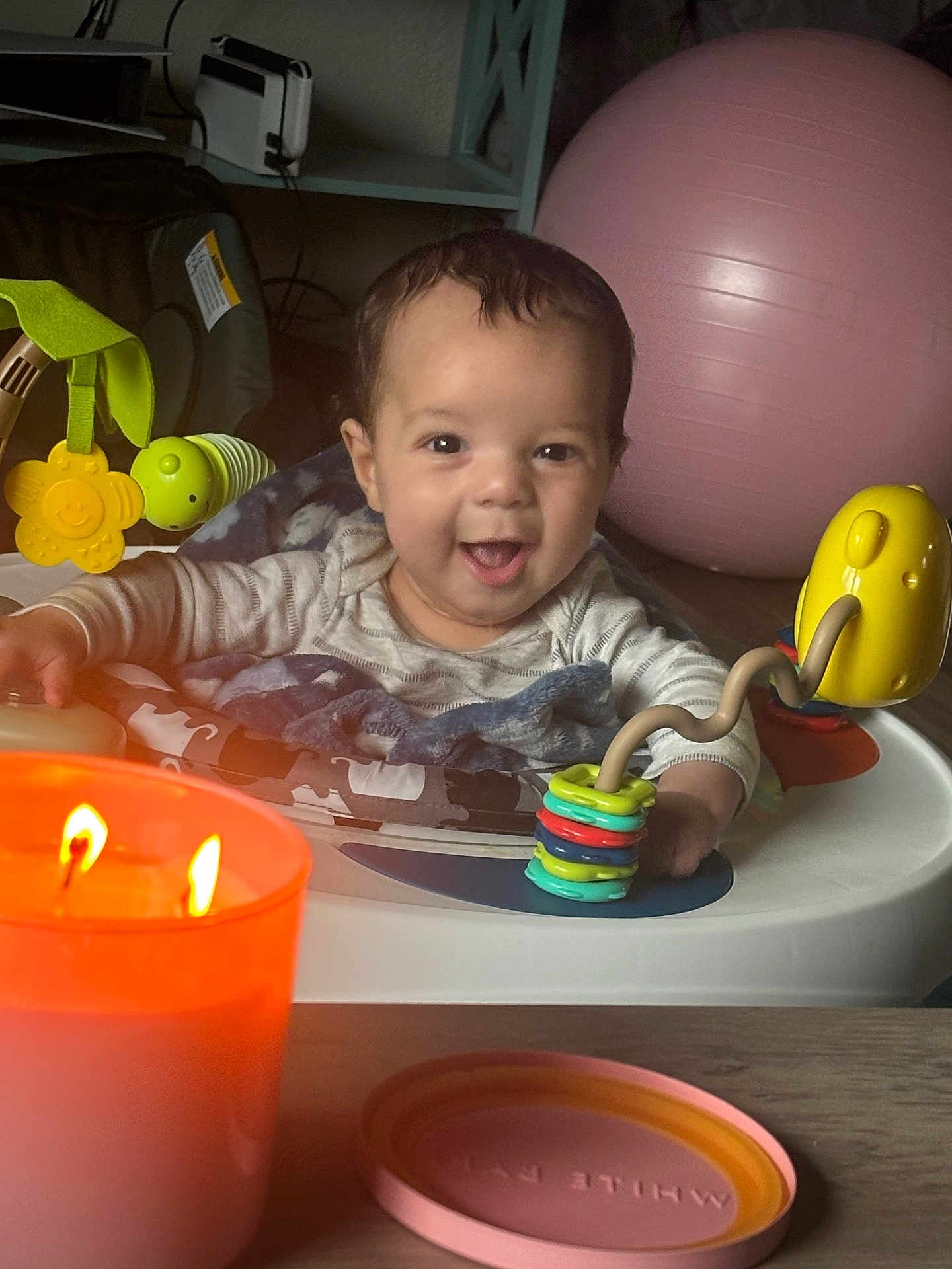 Jeremiah joined the competition — help win amazing prizes! baby, child, smiling, toy, activity_center, candle, indoor, play, happy, face, person, table, colorful, exercise_ball, blanket, infant, lighting, closeup, home, cute