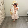 Mía Blanca is registered to the contest to win money with this photo: child, girl, toddler, hat, sunglasses, purse, dress, jacket, sandals, indoor, hardwood_floor, dresser, window, standing, smiling, accessories, fashion, playful, cute, portrait