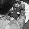 baby, child, infant, sunglasses, suit, formalwear, adult, tattoo, arm, portrait, black_and_white, indoor, cushion, pillow, seated, fashion, family, parent, close_up, humorous