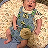 baby, infant, child, smiling, portrait, sitting, cushion, rainbow_pattern, carpet, overalls, dinosaur, alien, milestone, two_months, happy, indoor, close_up, barefoot, baby_clothing, photography
