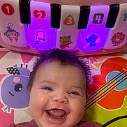 Mikiah joined the competition — help win amazing prizes! baby, infant, smiling, face, tooth, toy_piano, fisher_price, colored_lights, playmat, patterned_clothing, happy, portrait, cute, indoors, music, instrument, closeup, cheeks, hair, expression