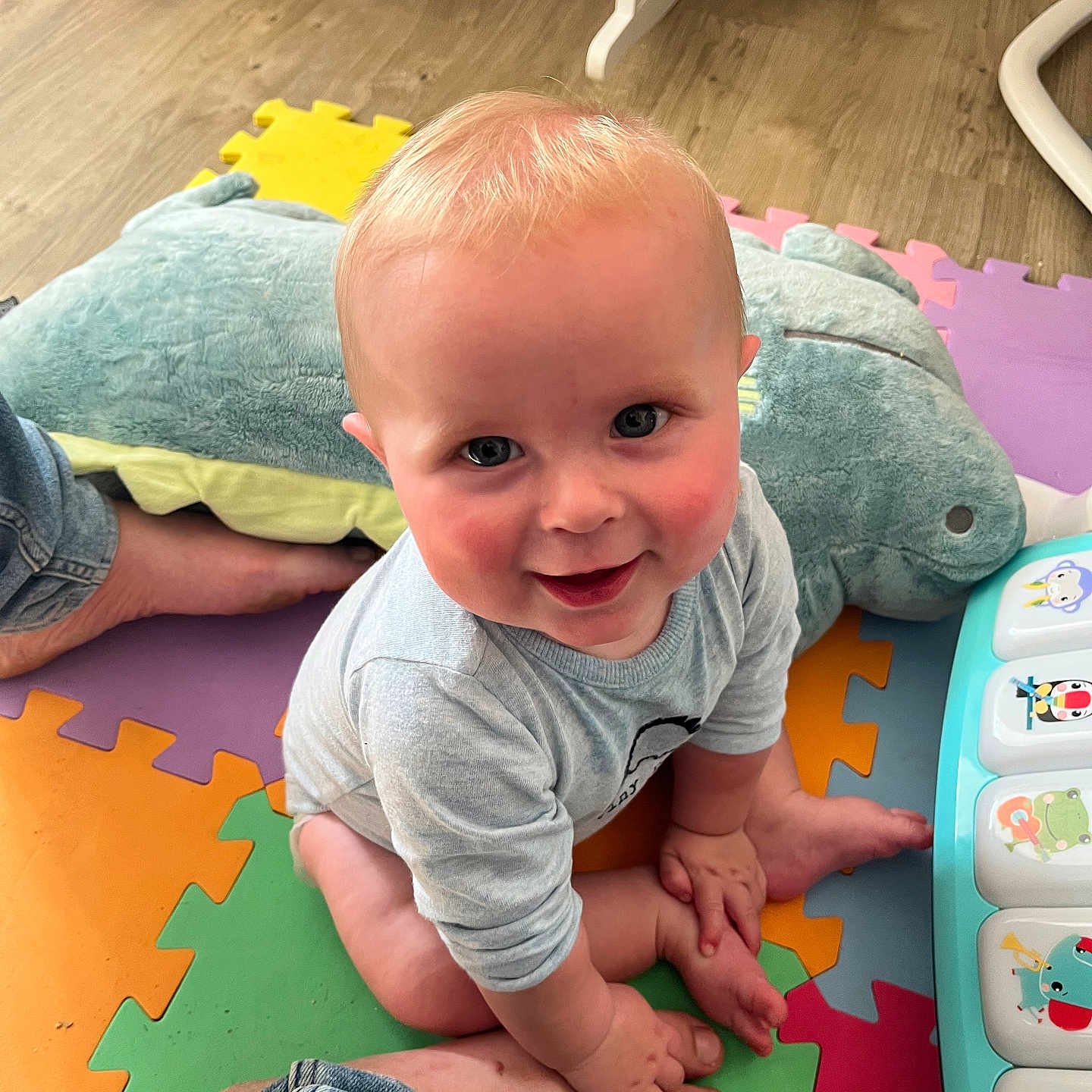Oliver is registered to the contest to win money with this photo: baby, blue_eyes, child, clothing, colorful, crawling, cute, floor, foot, hand, happy, indoor, infant, musical_toy, person, playmat, playroom, plush_toy, smiling, toy