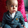 baby, child, suit, pinstripe, brown_shoes, bed, cushion, red_cushion, curious, portrait, indoors, fashion, cute, sitting, clothing, person, young_child, face, eyes, stylish