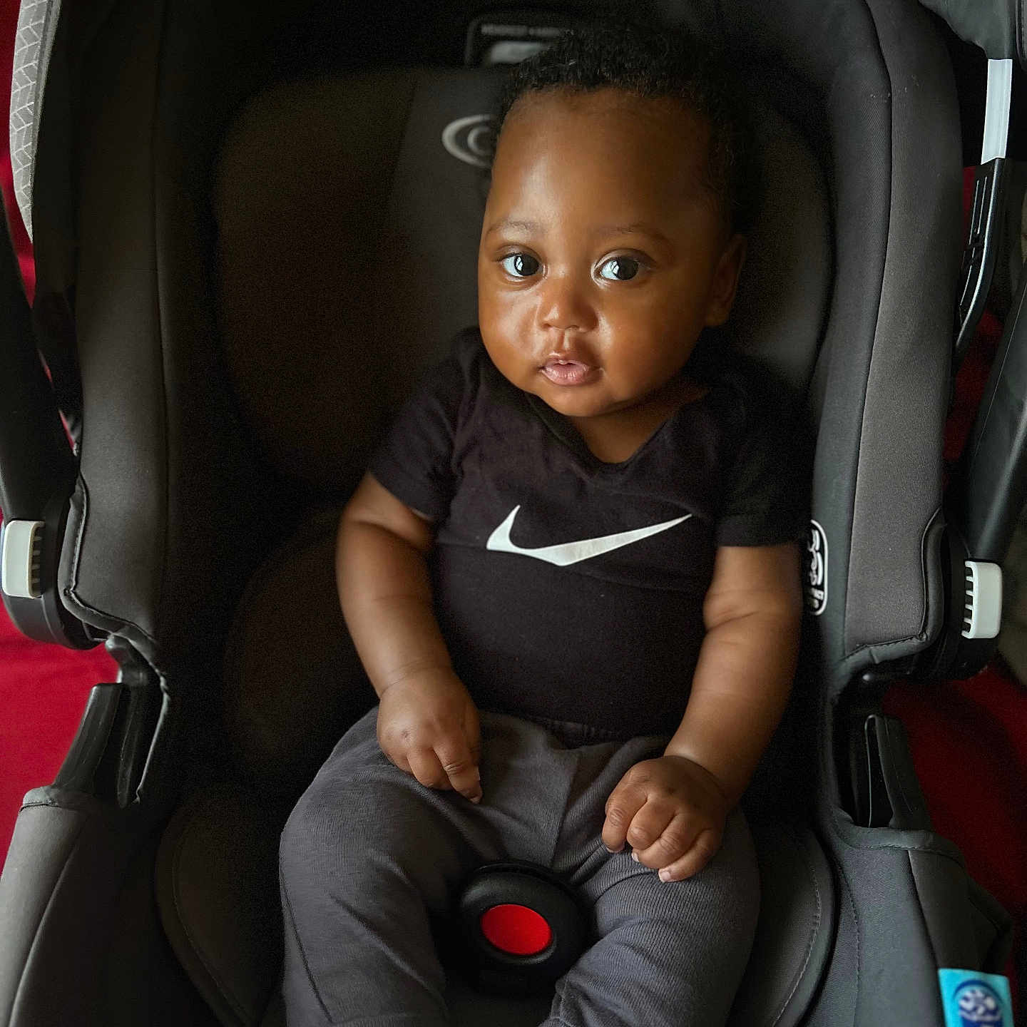 Ayvn joined the competition — help win amazing prizes! baby, black_shirt, car_seat, child, clothing, comfort, curious, cute, eyes, face, grey_pants, hands, indoor, infant, nike_logo, portrait, seat_belt, sitting, socks, young_child