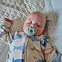 baby, sleeping, pacifier, onesie, whale_pattern, blanket, quilted, bed, infant, peaceful, nap, child, cute, pale_skin, closed_eyes, soft_lighting, indoor, cozy, resting, toddler