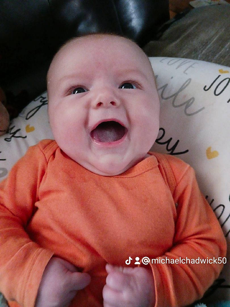Michael is registered to the contest to win money with this photo: baby, baby_toddler_clothing, cheek, chin, eye, facial_expression, finger, gesture, happy, head, iris, lip, mouth, nose, person, pink, product, skin, sleeve, smile